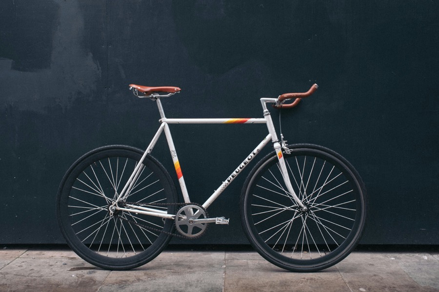 White road bike with brown saddle against a dark wall